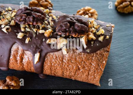 On a wooden board, a Swiss roll with hazelnuts, buttercream filling, and dark chocolate topping. This is perfect for any day or New Year's treats. Stock Photo