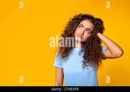 Curious woman with hand in hair looking aside at free space Stock Photo