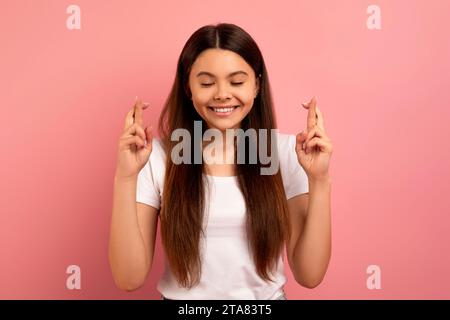Hopeful teen girl crossing fingers and making wish Stock Photo