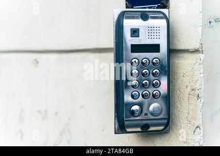A close-up of a modern intercom system with a built-in camera and keypad, securely mounted on a house wall, providing safe access to the property and Stock Photo