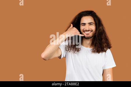 Cheerful Arabic young man gesturing Call Me against beige backdrop Stock Photo