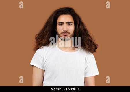 Studio Portrait Of Sad Arabic Guy With Long Curly Hair Stock Photo