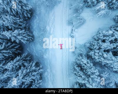 Aerial view of woman lying on the snow on mountain road in beaut Stock Photo