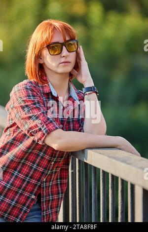 A redhead woman poses gracefully in the warm glow of an autumn sunset Stock Photo