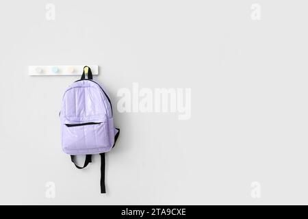 School backpack hanging on light wall Stock Photo