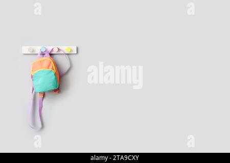 Stylish school backpack hanging on light wall Stock Photo
