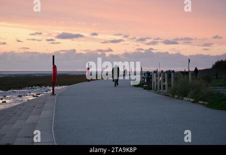 A lone cyclist races along the promenade at sunset, Lytham St Annes, Lancashire, United Kingdom, Europe Stock Photo