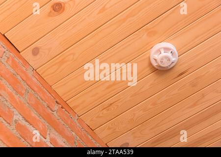 Fire alarm on wooden ceiling in interior smoke detector safety and home protection from dangerous with fire, close-up. Stock Photo