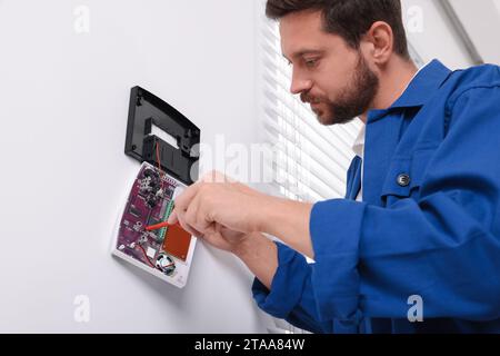 Technician installing home security alarm system on white wall indoors Stock Photo