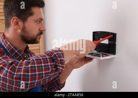 Technician installing home security alarm system on white wall indoors Stock Photo