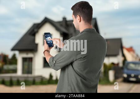 Man using home security system application on smartphone outdoors Stock Photo