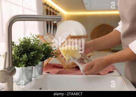 Woman washing glass at sink in kitchen, closeup Stock Photo