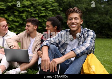 Group of happy young students learning together on green grass in park Stock Photo