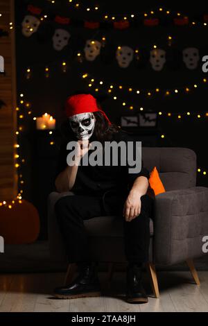 Man in scary pirate costume with skull makeup against blurred lights indoors. Halloween celebration Stock Photo