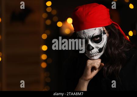 Man in scary pirate costume with skull makeup against blurred lights indoors, space for text. Halloween celebration Stock Photo