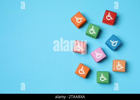 Inclusion concept. Colorful cubes with international symbols of access on light blue background, top view Stock Photo