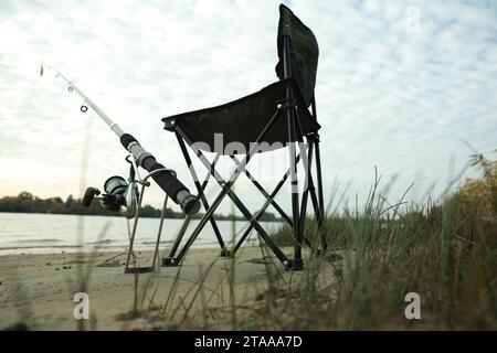 Camping chair with fishing rod at riverside on sunny dayの素材