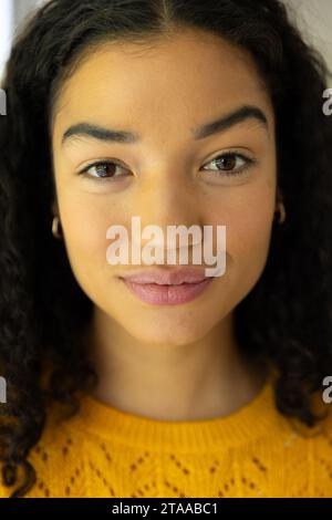 Close up portrait of biracial woman in yellow sweater at home Stock Photo