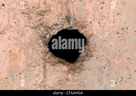 Hole circle round in concrete color old dirty wall, isolated black, close-up. Stock Photo