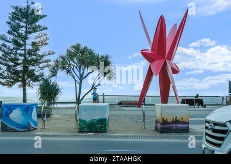 Surfers Paradise Australia; September 23 2023; People on The Esplanade at dawn near large red sculpture called All Eyes on Us: The Commonwealth Star. Stock Photo