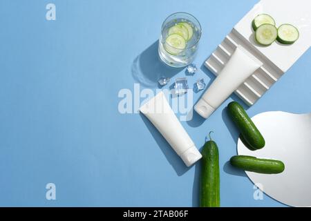 Two white tubes decorated with a staircase, ices and a mirror. A glass of cucumber detox water is featured. Skin care concept with empty label for Cuc Stock Photo