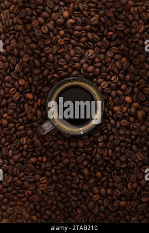 Top view of glass cup of coffee espresso displayed on brown roasted coffee beans background. Minimal scene for advertising. Active caffeine in coffee Stock Photo