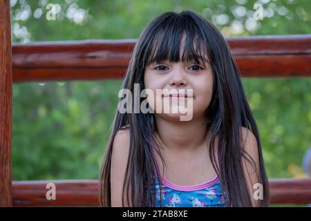 Portrait of a cute Argentinian girl with long hair, who plays in the park. Stock Photo