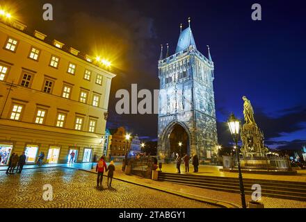 Pedestrian Crusaders Square with Gothic Old Town Bridge Tower and monument of King Charles IV in evening lights, Prague, Czechia Stock Photo