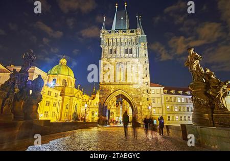 Brightly illuminated Old Town Bridge Tower with statues on the Charles Bridge in the foreground, Prague, Czechia Stock Photo