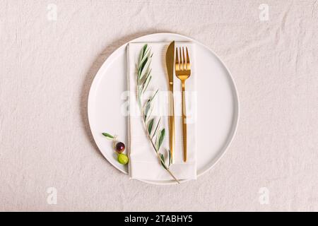 Plate with golden color cutlery and olive branch, elegant table setting, top view Stock Photo