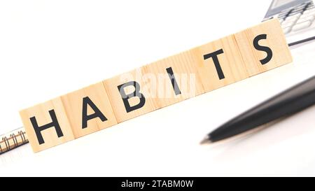 HABITS word assembled from wooden cubes next to a calculator, pen and notepad Stock Photo