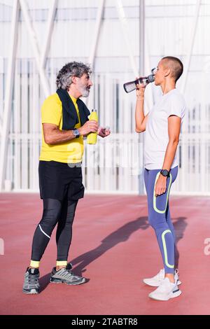 man drinking water with trainer before training Stock Photo