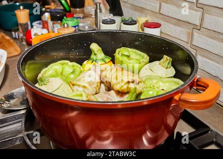 Stuffed zucchini and peppers are cooked in a saucepan on a gas stove. Stock Photo