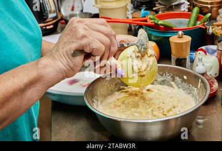 Close-up shot of a cook carefully stuffing round zucchinis with a savory meat filling, showcasing the process in a sophisticated, modern kitchen setti Stock Photo