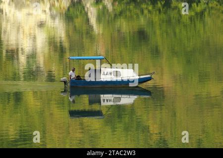 small cabin boat sailing on the water reflection of Perucac Lake - Drina River, Bajina Basta, Serbia Stock Photo