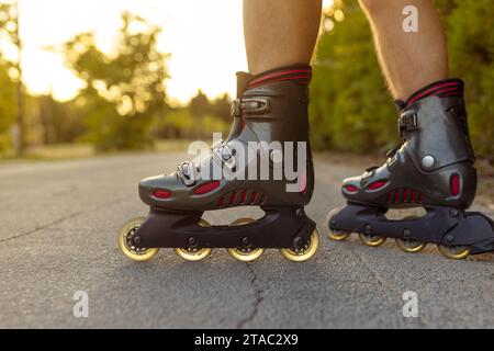 unrecognizable feet with rolling skate close up on rural paved street with sun flare or back light low angle view Stock Photo