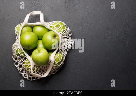 Mesh bag with fresh green apples on stone table. Flat lay with copy space Stock Photo