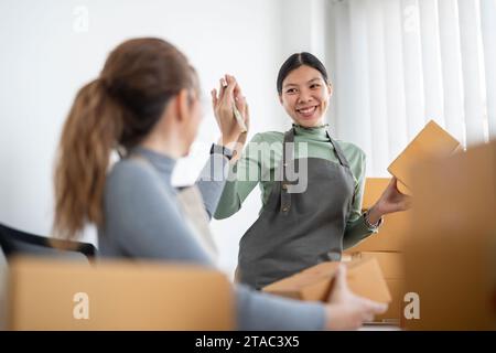 Cheerful store owner high fiving in shop. Happy young businesswomen celebrating their success as a team. Two female entrepreneur running an ecommerce Stock Photo