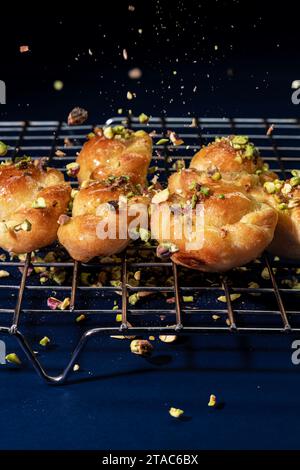 Sweet buns sprinkled with pistachios on a blue background. Stock Photo
