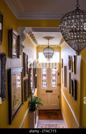 Glass pendant shades with stained glass door panels in yellow hallway of late 19th century West London home. Stock Photo