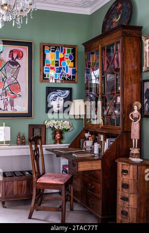 Antique wooden writing desk and cabinet with framed art in late 19th century West London home. Stock Photo