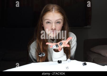 Teenage girl rolls dice and tosses dice from her hands Stock Photo