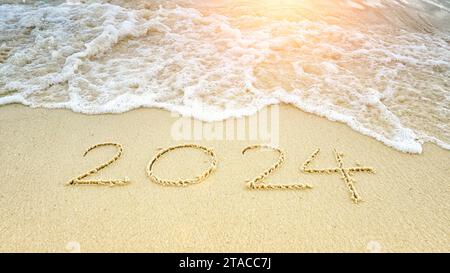 happy new year 2024. number 2024 write on sandy beach with ripple ocean wave splash with white bubble. turning to year 2024 Stock Photo