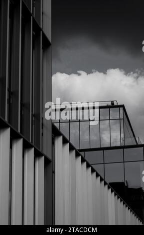 facade of a glass office building against a dark sky. black and white modern architecture Stock Photo