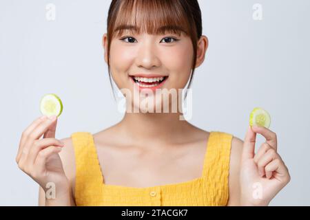 Organic cosmetics concept. A young girl with clean skin holds cucumber slices near her face. Stock Photo