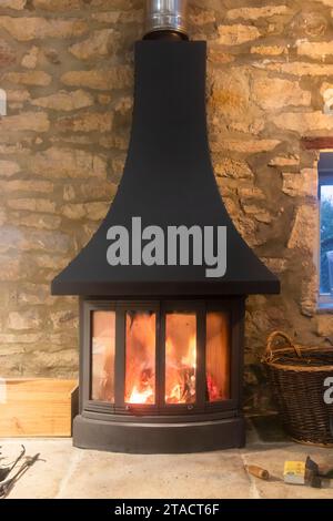flames in a log burning stove with stone wall Stock Photo