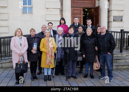 (from left) Lynda McManus, Martina Dillon, Michael McManus, Donna McManus, Phoenix Law trainee solicitor Harry Robinson, Mairead Kelly, Grainne Teggart, Amnesty International UK's Deputy Director for Northern Ireland, Brigid Hughes, Phoenix Law solicitor Gavin Booth, Deirdre Hughes, Irene McEvoy, Phoenix Law solicitor Darragh Mackin, Sinead Marmion and John McEvoy, at the High Court in Belfast following final arguments in legal challenge to Goverment legacy act. Picture date: Thursday November 30, 2023. Stock Photo