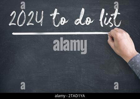 Close up of human hand writing 2024 New Year Resolution Check List on Blackboard Stock Photo