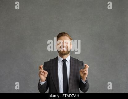 Businessman keeping his fingers crossed, believing in luck and hoping for the best Stock Photo