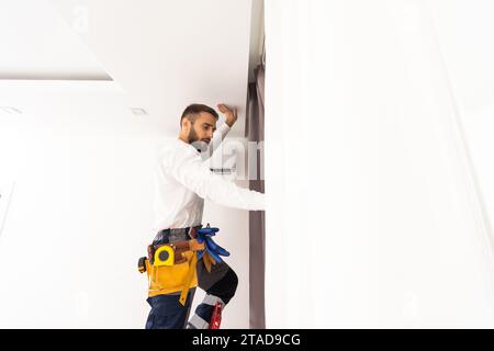 Man hanging window curtain indoors. Interior decor element Stock Photo